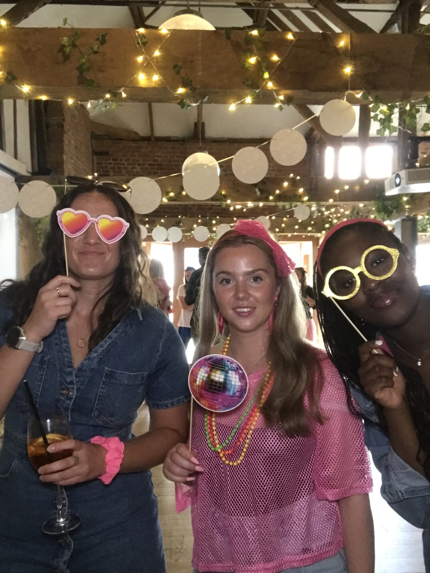 Three UK team members in the photobooth with a disco ball prop