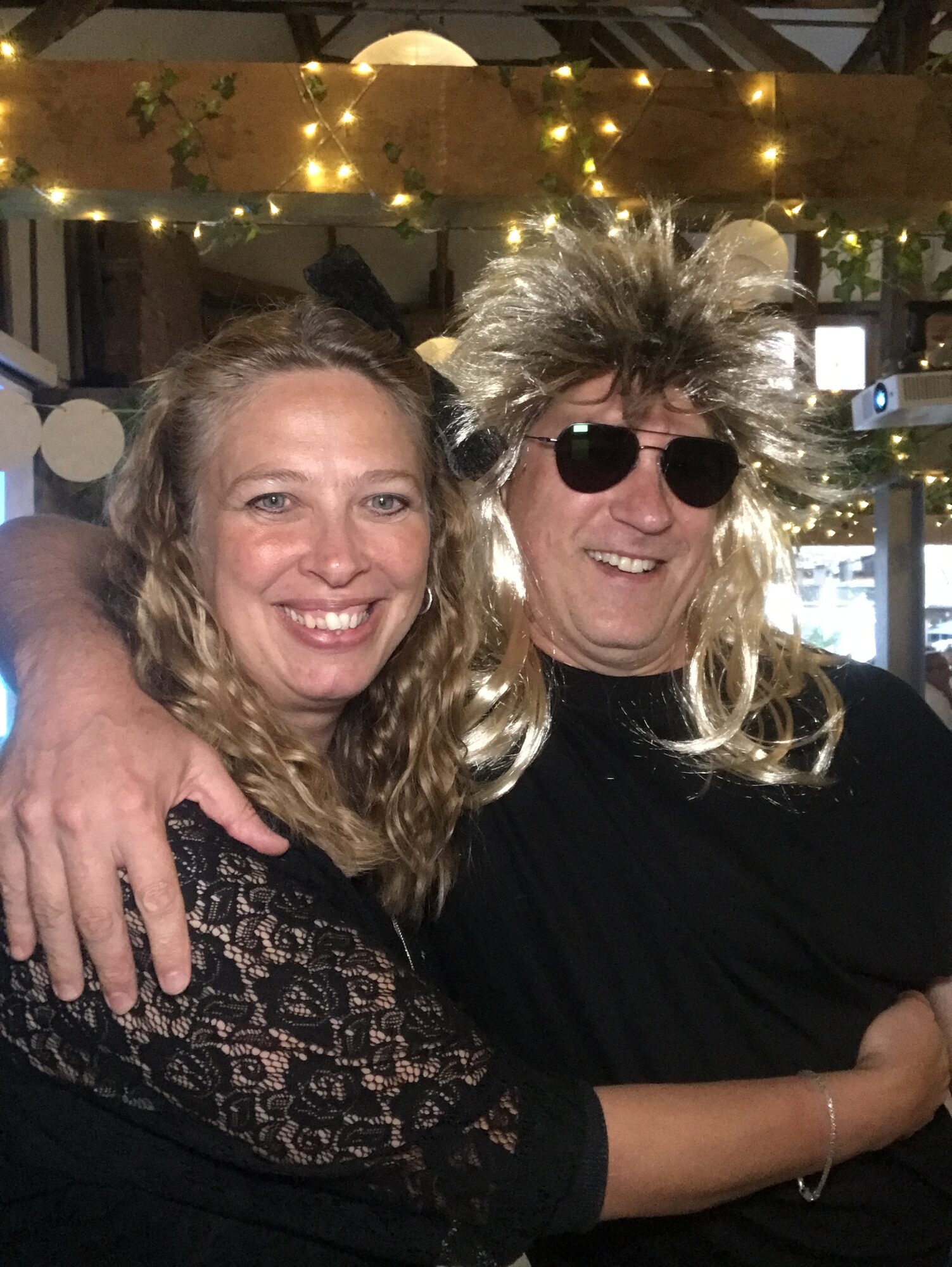 Two UK team members wearing party wigs at the 40th anniversary celebration