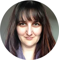 Dr. Silvia Smith smiles at the camera. She has dark hair and a fringe, and appears against a gray background.