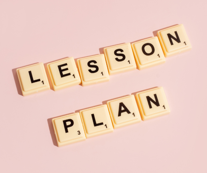 A photo of scrabble tiles on a pink background. The scrabble tiles spell out "LESSON PLAN".