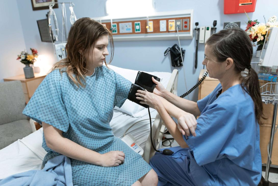 a nurse puts a blood pressure cuff on a woman
